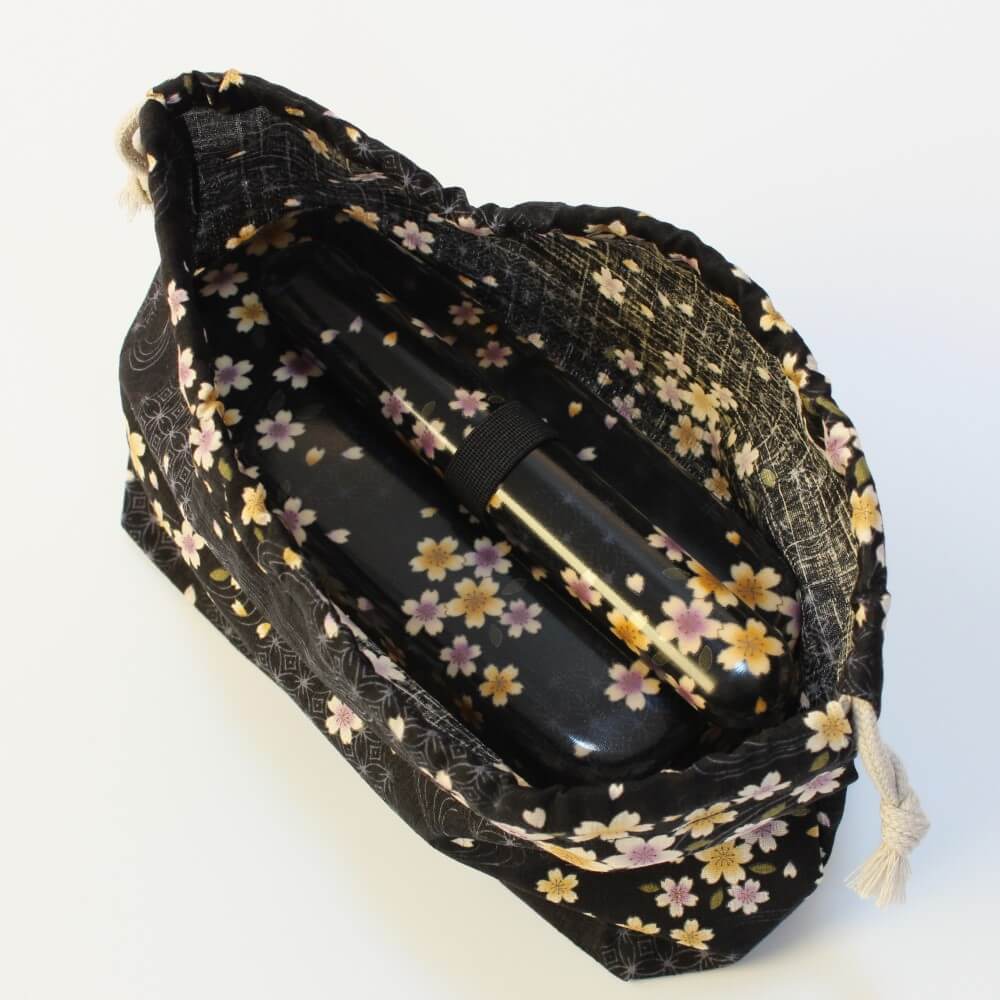 chopsticks and bento box fully inside black bento kinchaku bag