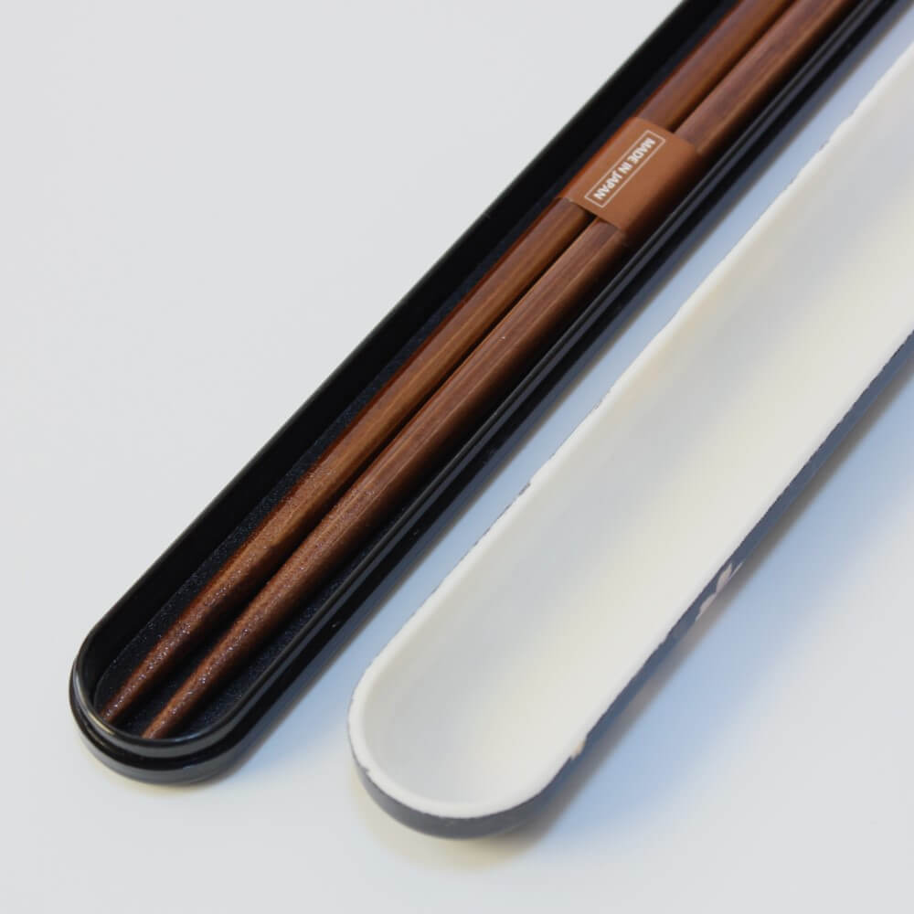 Brown chopsticks in a black case on a white background