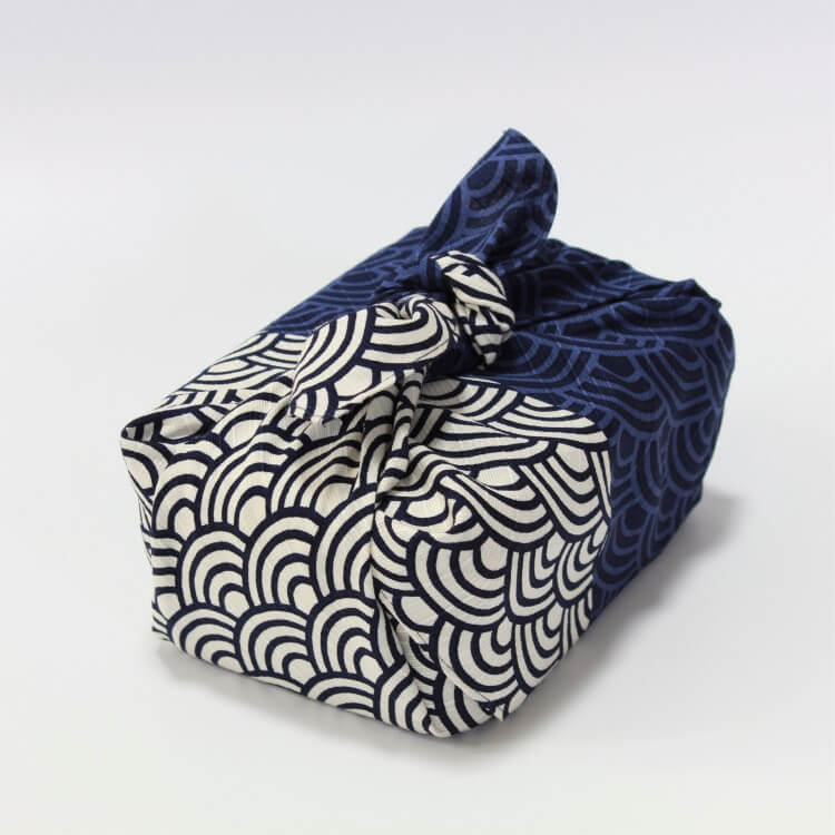 angled shot of bento box wrapped with wave patterned japanese wrapping cloth furoshiki