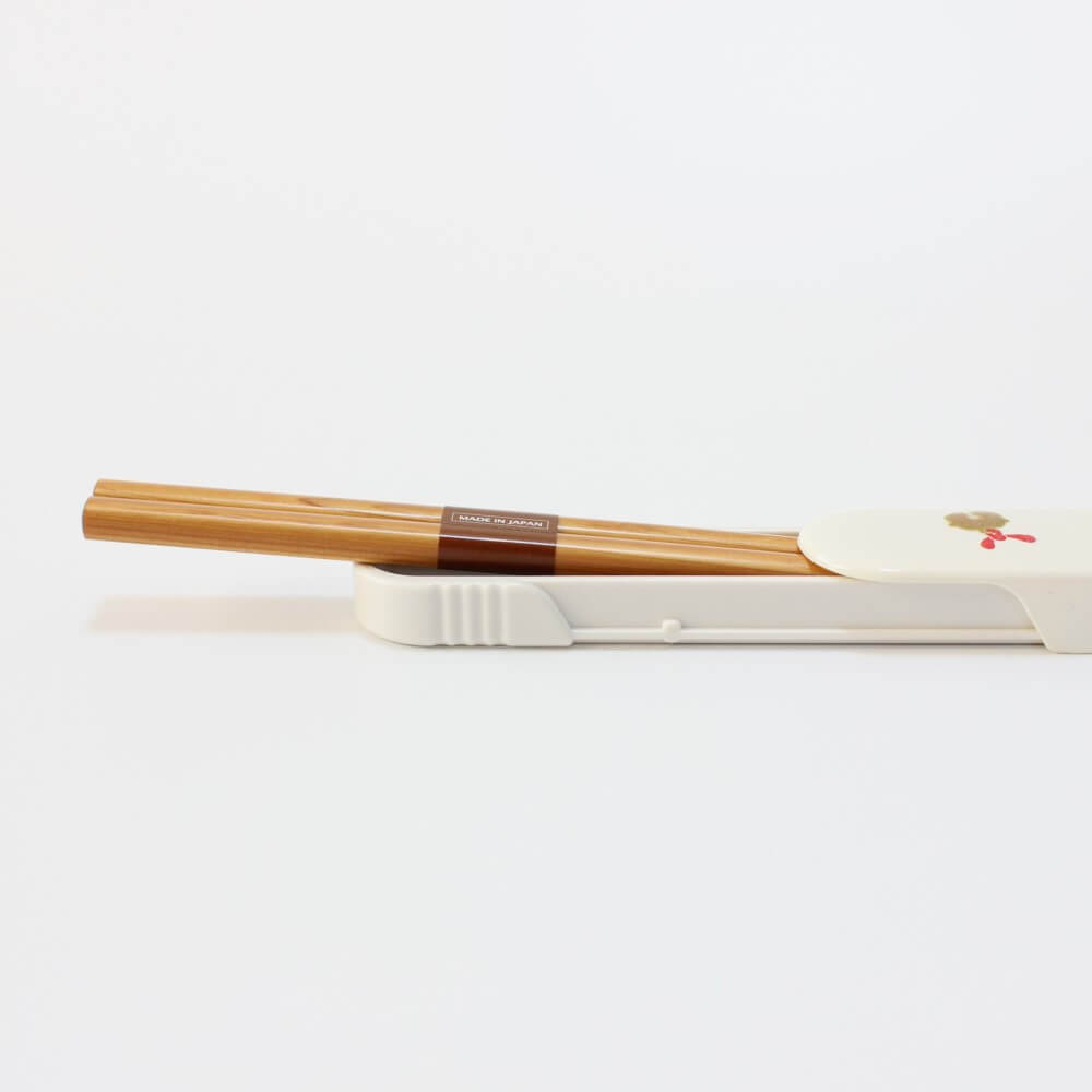 side view of chopsticks halfway inside white chopsticks case