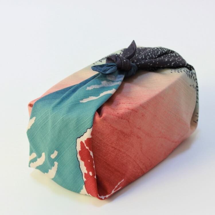 top angle shot of bento box wrapped in furoshiki with hokusai artwork
