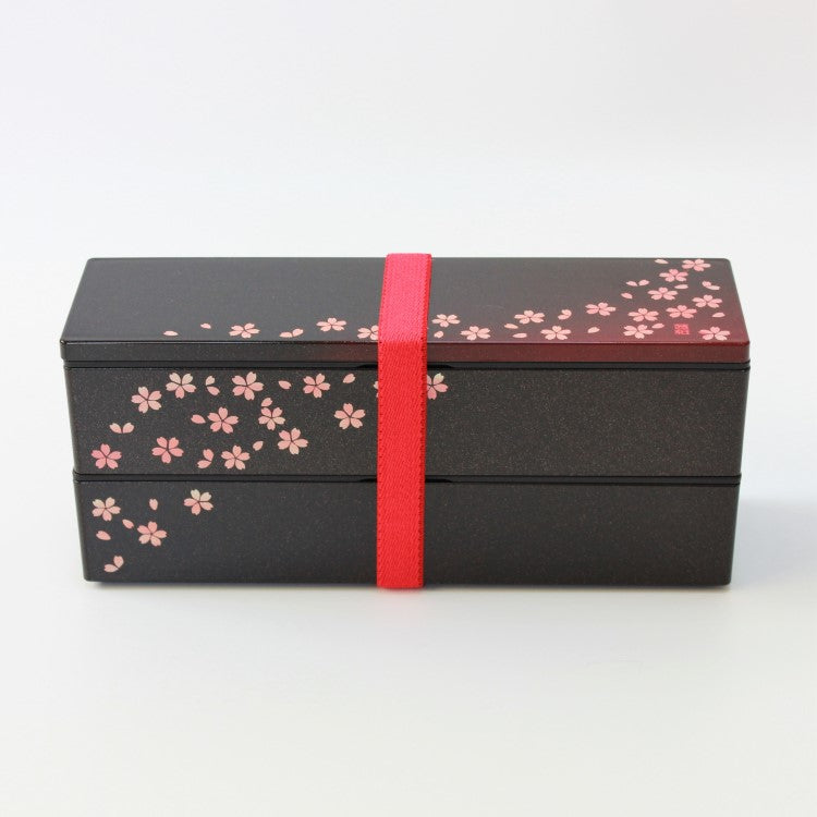 Side view of 2 tier long slim bento box with red elastic band securing the box