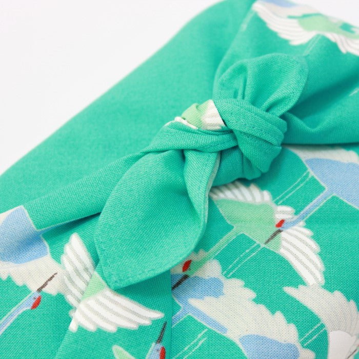 Close up showing the knot of a bento box wrapped with hime musubi crane turquoise furoshiki