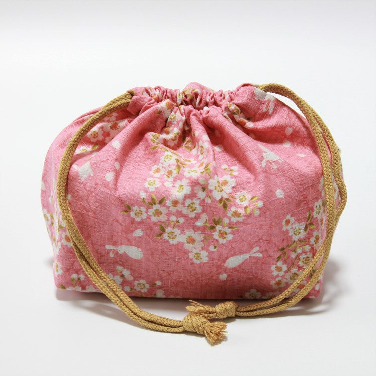 Side view of the sakura usagi pink lunch bag, with orange yellow strings. 