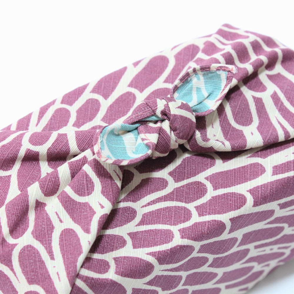 The sage blue colour in the knot of a tied furoshiki shows a calm contrast to the purple colour.