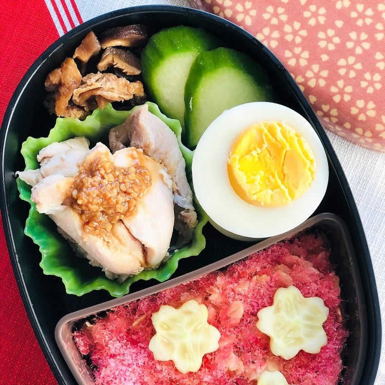 Green square divider cup inside a bento box with food
