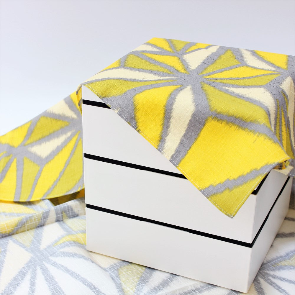 Yellow and Green Furoshiki Japanese wrapping cloth laid over a picnic bento box from Majime Life. 