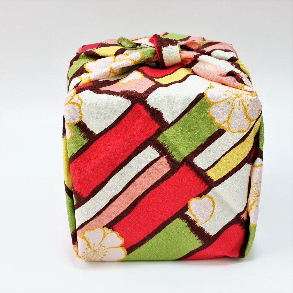 Front view of a picnic bento box wrapped in the retro designed modern girl sakura multi furoshiki Japanese wrapping cloth.