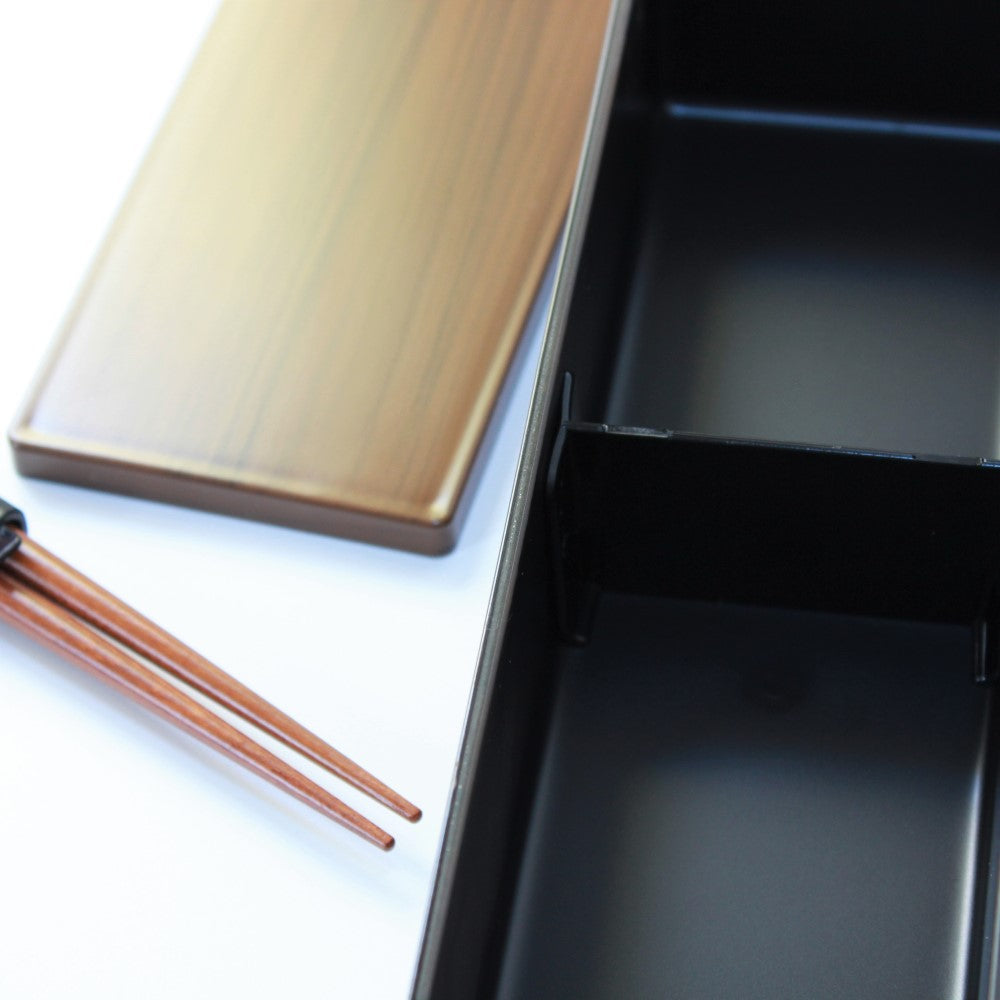 Close up shot showing chopsticks, woodgrain lid and inside of bento box