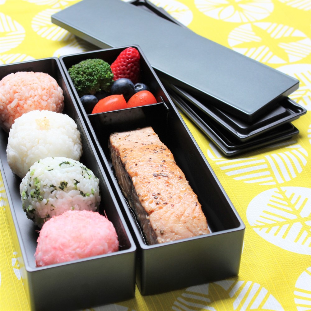 Riceballs, salmon, fruits and vege organized in this long slim 2 layered bento box from Majime Life