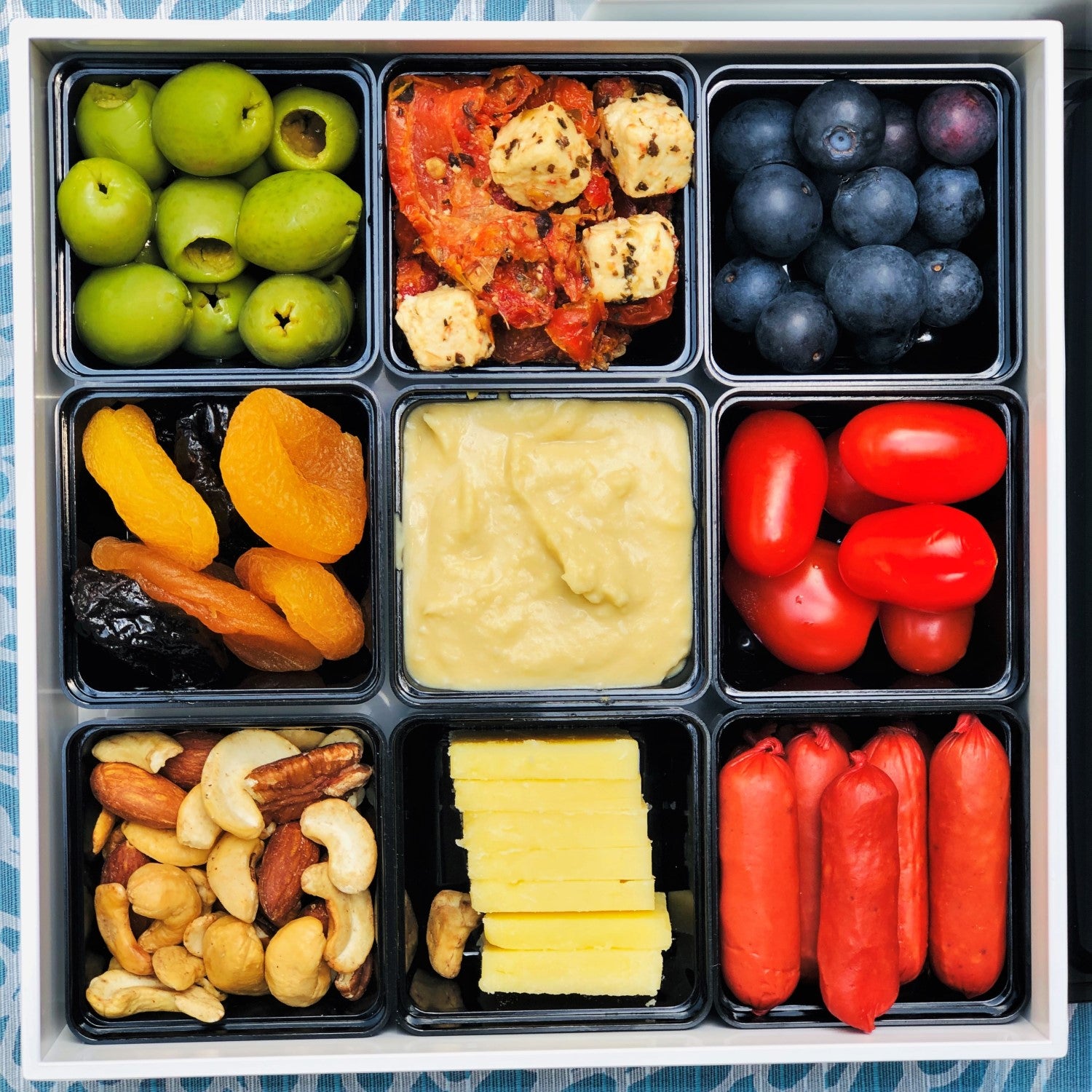 Nine different foods in the small containers of this picnic bento box.