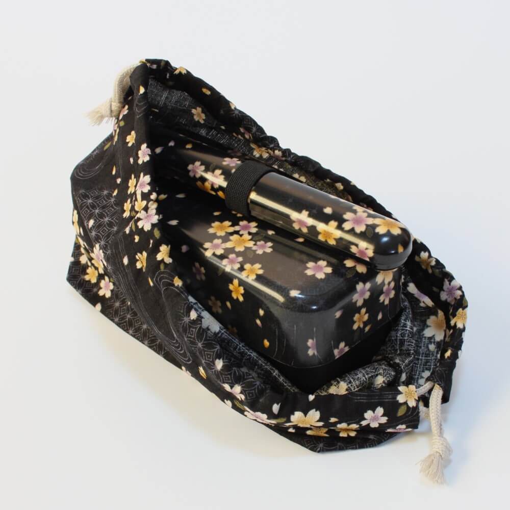 bento box and chopsticks inside black bento bag with matching sakura flowers