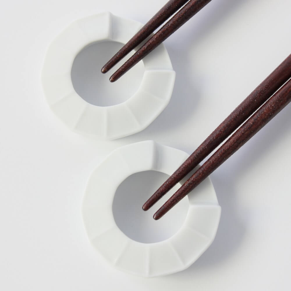 close up of chopsticks tips resting on ring shaped chopsticks rests