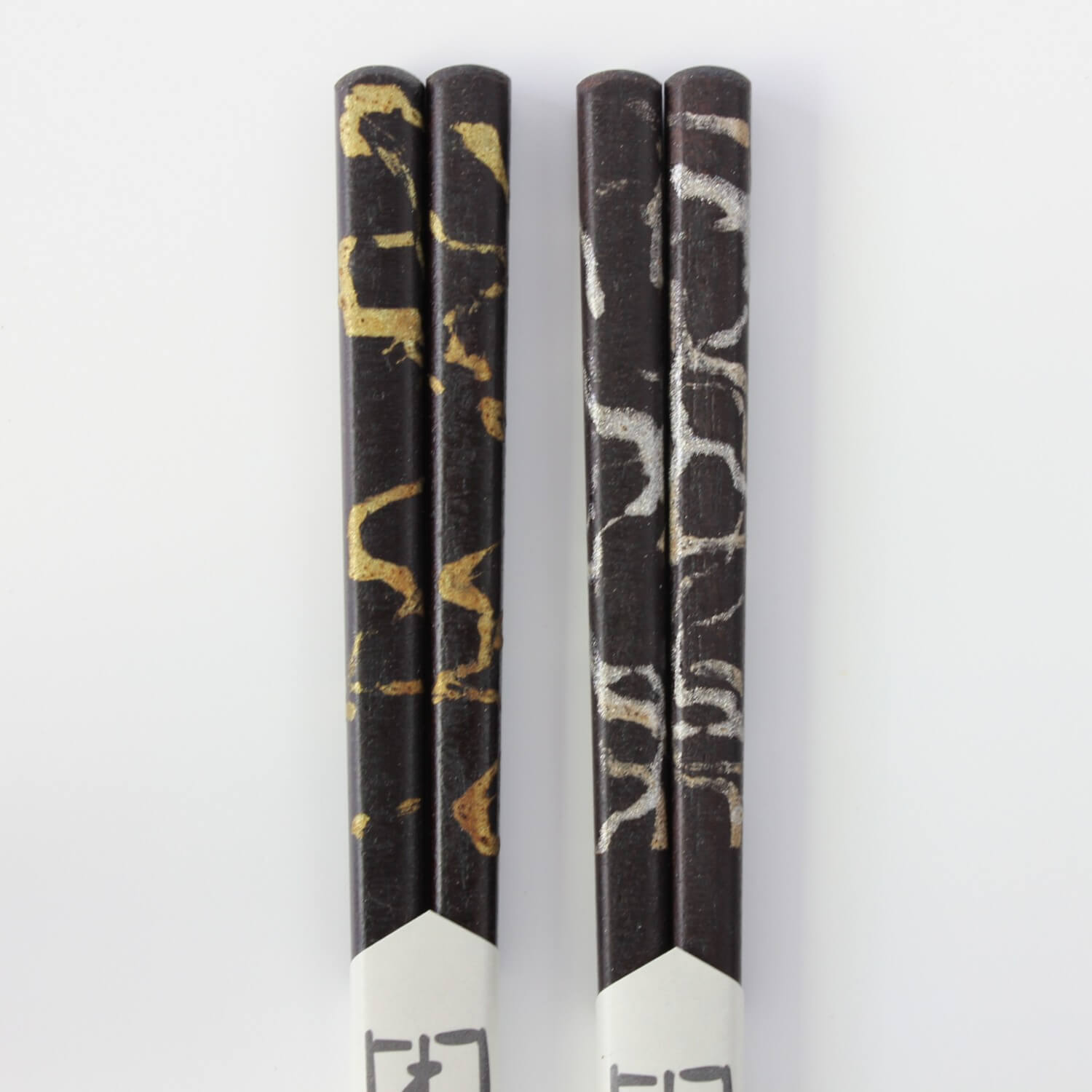 close up of handles of gold and silver cloud chopsticks made from ebony wood