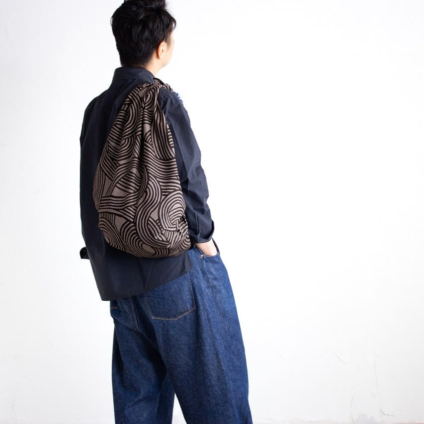 man carrying furoshikki bag knot dark grey blue design