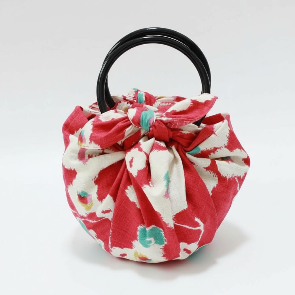 Floral fabric teapot cozy with a black handle on a white background