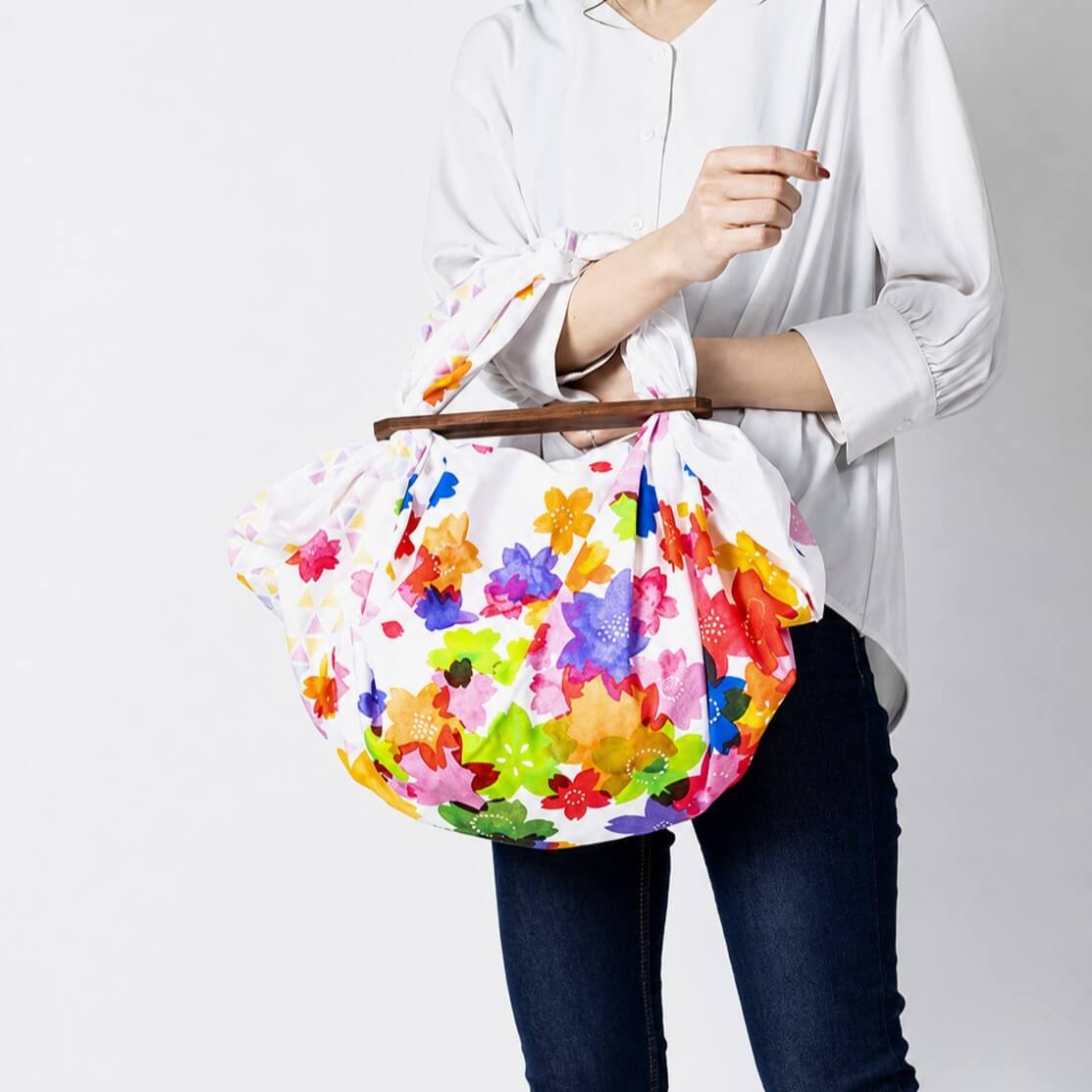 lady holding a furoshiki bag made with the colourful sakura 100cm furoshiki