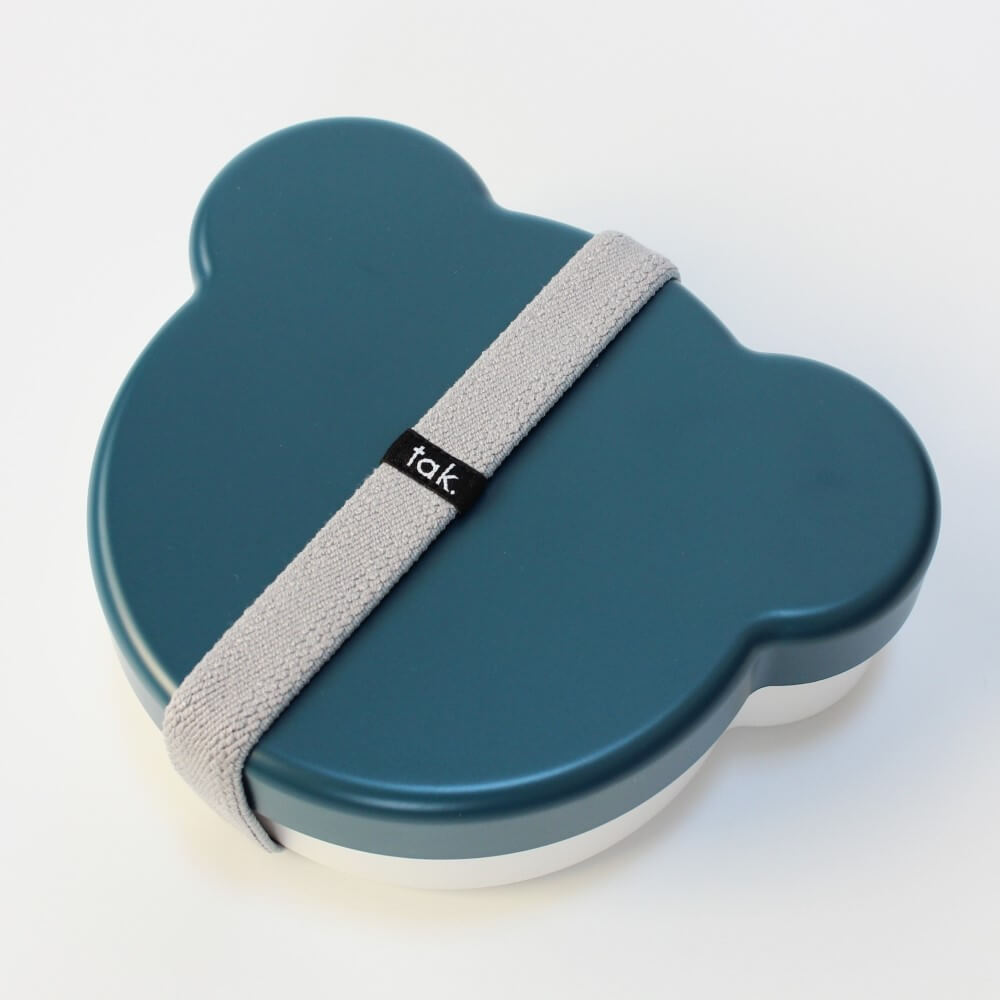 Blue bear-shaped container with a gray strap and 'tak' brand logo on a white background
