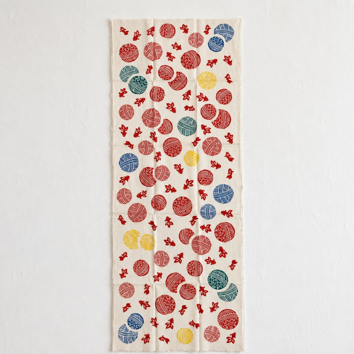 rectangular tenugui with temari balls and goldfish design on a white wall