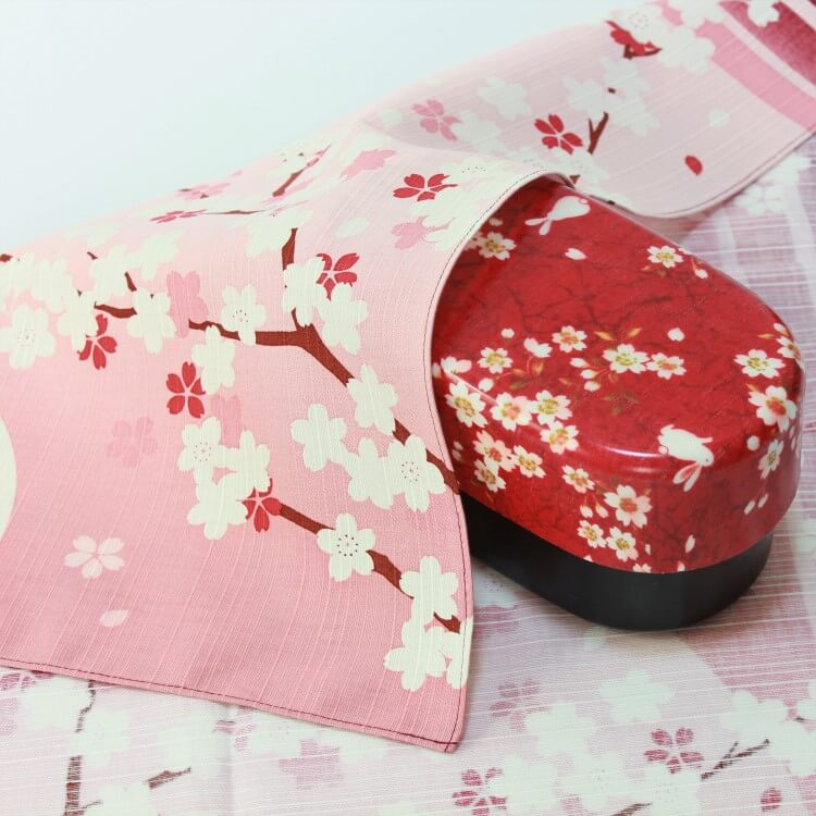 sakura scape japanese wrapping cloth covering a red bento box