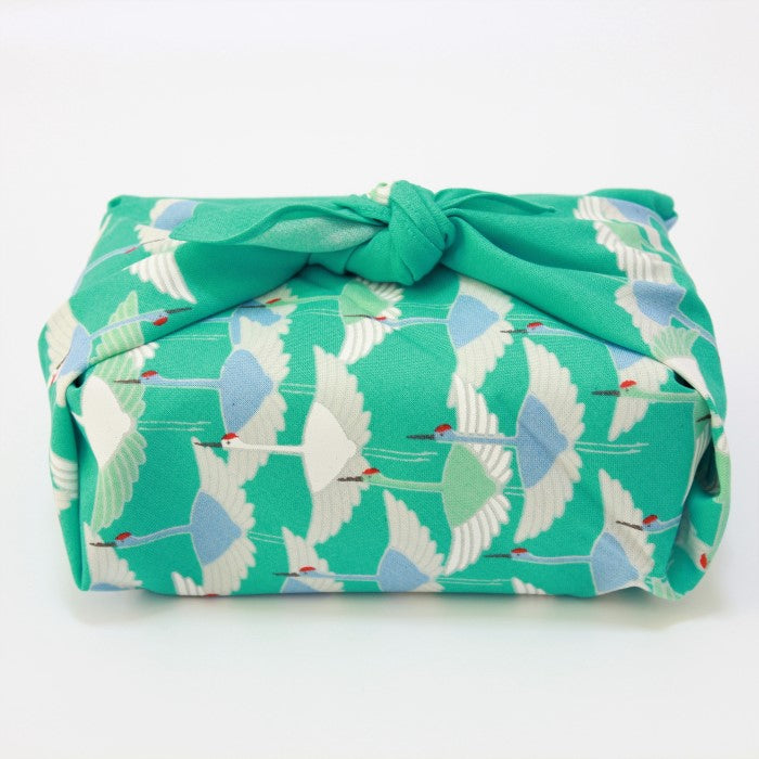 furoshiki japanese wrapping cloth with cranes on a turquoise background wrapped around a bento box