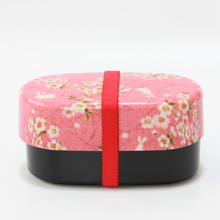 Side view of Sakura Usagi Pink 2 Tier Bento Box with red elastic lunch band