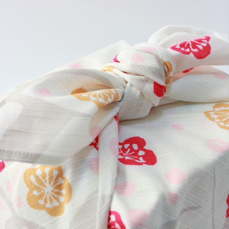 Clost up shot showing the know of a wrapped bento box. Wrapped in Japanese plum red and beige furoshiki yumeji takehisa