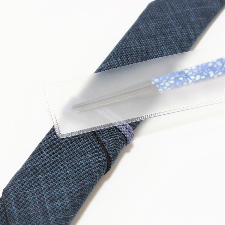 Plastic case covering the tips of a pair of chopsticks on top of a navy blue chopsticks case made of fabric
