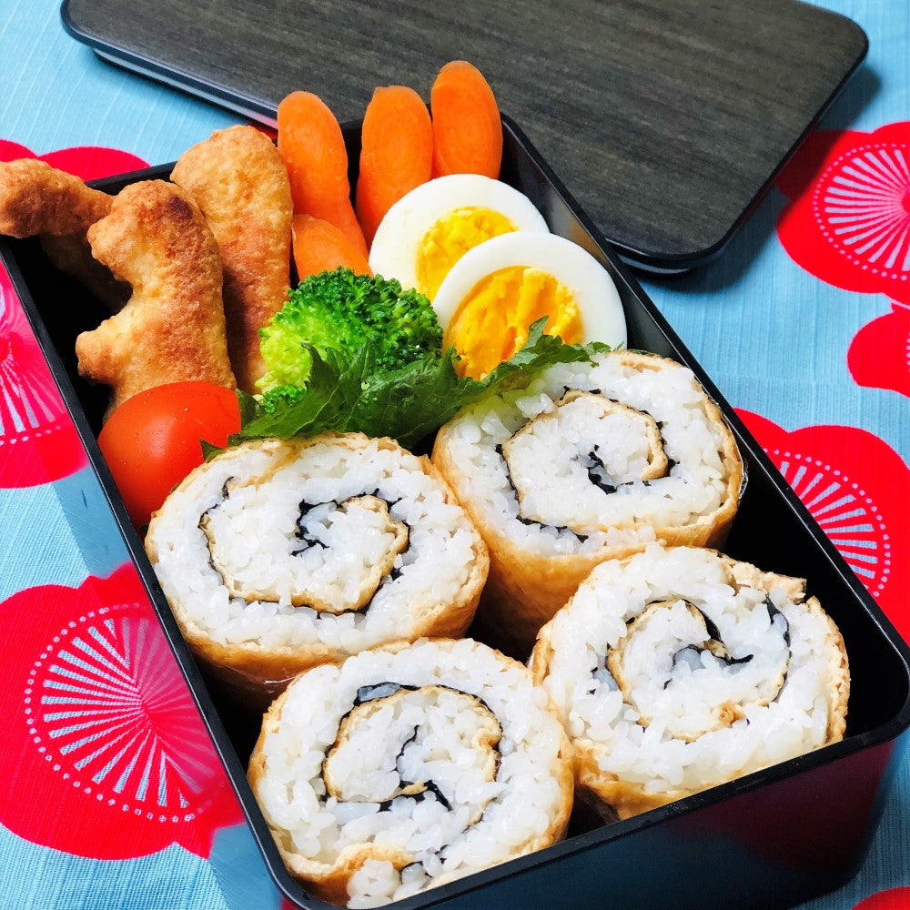 Packed bento box with sushi rolls and chicken nuggets and other sides
