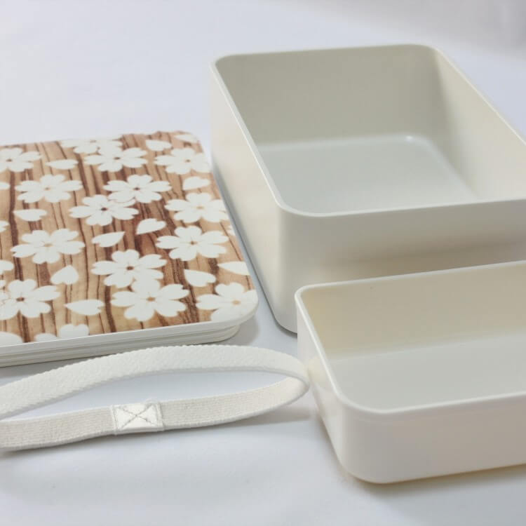 Opened bento box with inner divider and white lunch band laid out