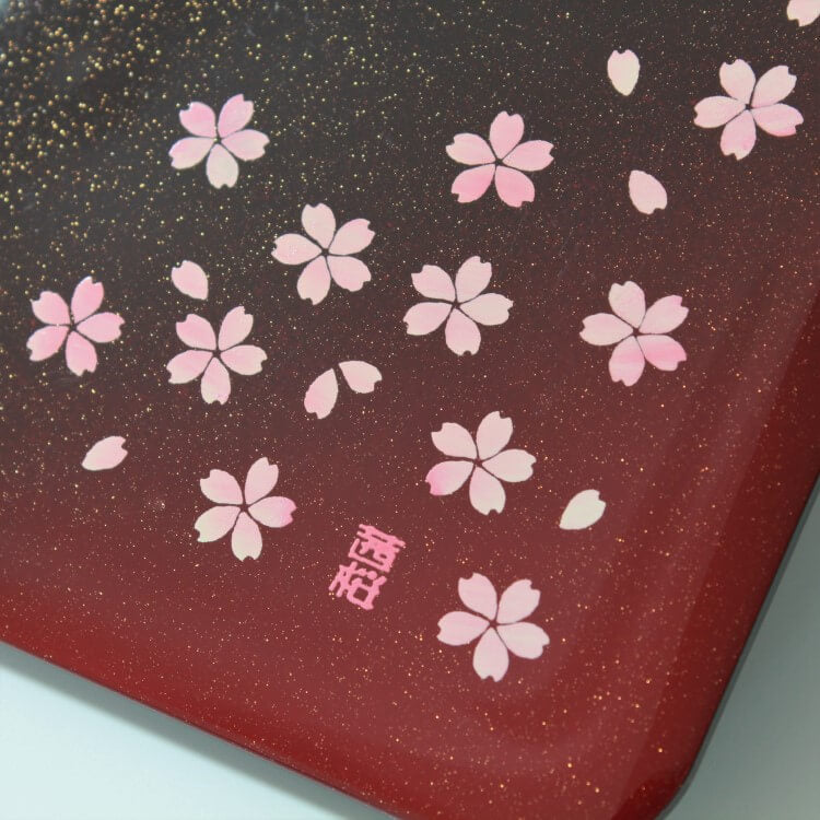 close up shot showing gold speckles and sakura patterns of the lid of sakura crimson bento box